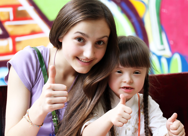 Two girls lifting their thumbs, one girl with disability